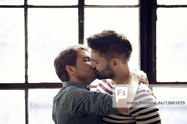Homosexuelles Paar küsst sich zu Hause am Fenster