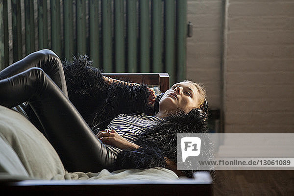 Woman listening music while lying on sofa at home