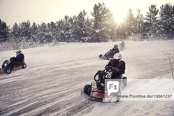 Boys racing on go-carts at snow covered field