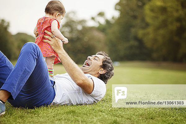 Happy father playing with baby girl at park
