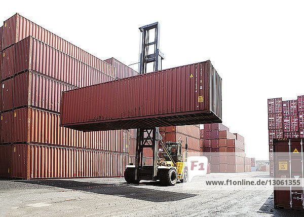 Person  die Frachtcontainer vom Gabelstapler im Handelsdock transportiert