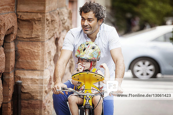 Vater und Tochter fahren Fahrrad auf der Straße in der Stadt