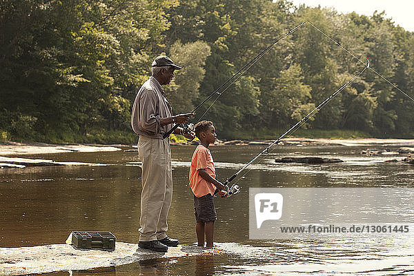 Grandfather and grandson fishing in lake