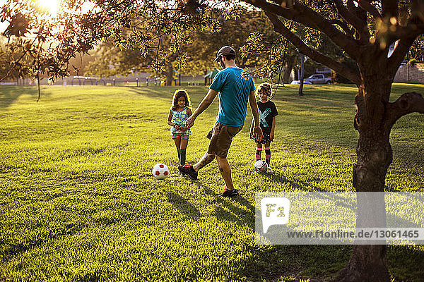 Vater spielt mit Töchtern im Park Fussball