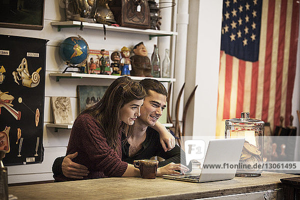 Glückliches Paar benutzt Laptop-Computer  während es im Café sitzt