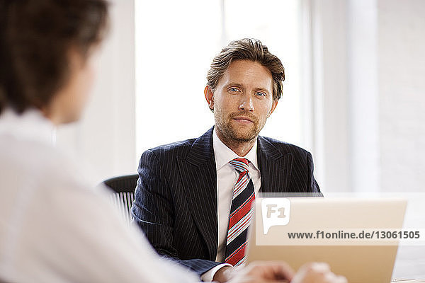Portrait of businessman sitting by coworker at office