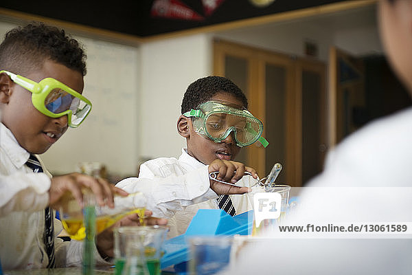 Schoolboys mixing chemicals at table in laboratory