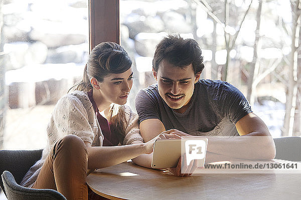 Couple using tablet while sitting at cafe