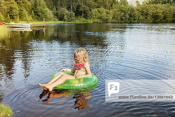 Mädchen sitzt auf einem aufblasbaren Ring am See
