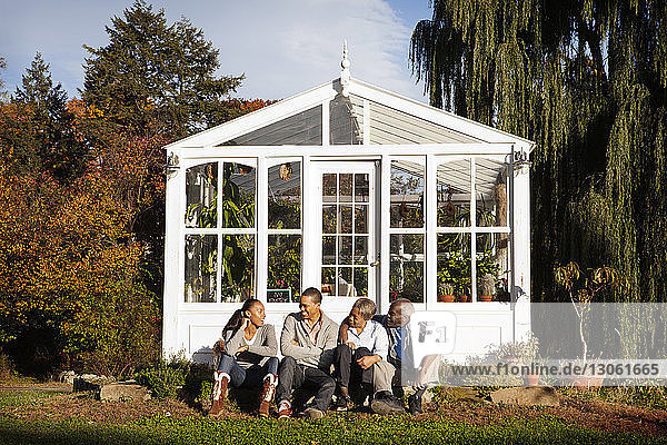 Happy family sitting against greenhouse