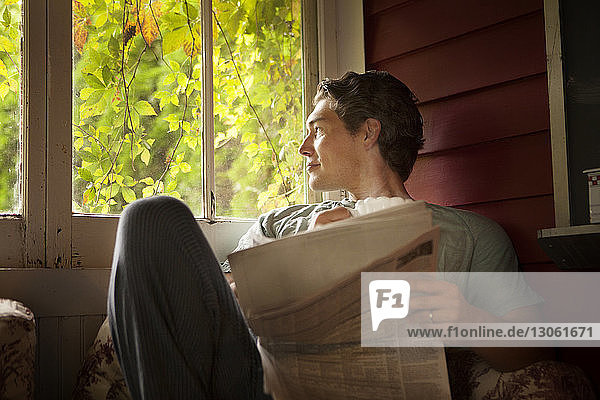 Mann schaut weg  während er zu Hause am Fenster sitzt