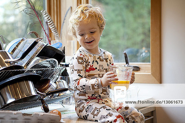 Junge hält Behälter  während er zu Hause auf der Küchenarbeitsplatte sitzt