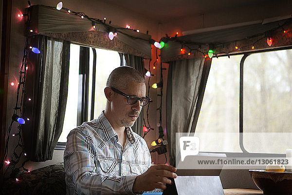 Mann benutzt Tablette,  während er im Wohnmobil sitzt