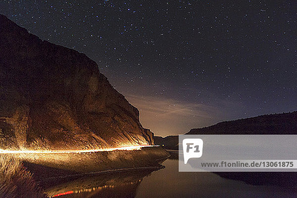 Szenische Ansicht eines beleuchteten Bergsees gegen den Sternenhimmel bei Nacht