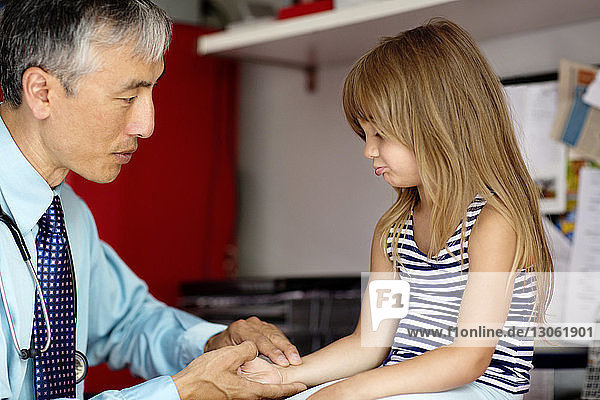 Ärztin untersucht Mädchen  während sie zu Hause ihre Hand hält