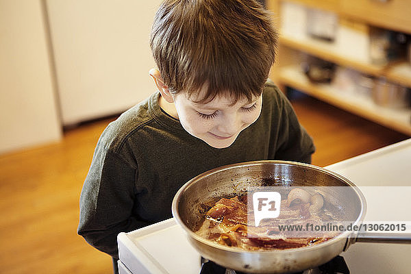 Curious boy looking at food on stove at home