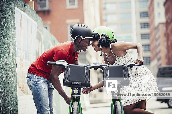 Seitenansicht eines lächelnden Paares  das mit dem Fahrrad auf der Straße steht