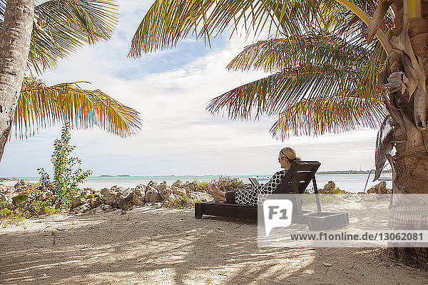 Woman resting on lounge chair at beach