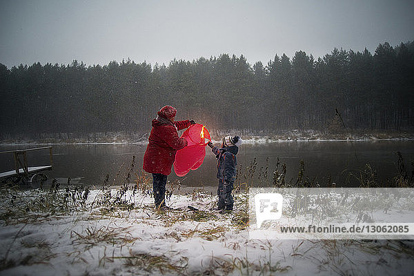 Grandmother and son holding paper lantern on snow covered field