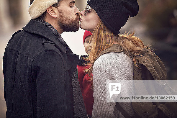 Paar küsst sich beim Tragen eines Mädchens im Park