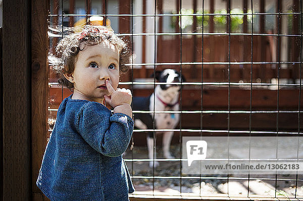 Kleines Mädchen schaut weg  während es am Zaun im Hinterhof steht