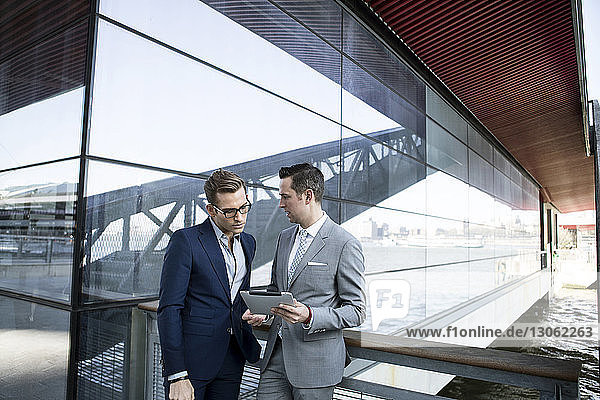 Businessmen using tablet computer while standing outside building