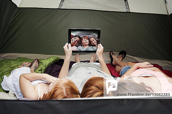 Brother taking selfie with sisters while lying in tent