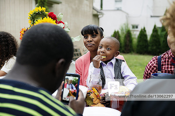 Teenager Junge fotografiert Mutter und Sohn am Picknicktisch