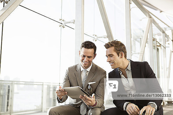 Glückliche Geschäftsleute mit Tablet-Computer auf der Bank sitzend