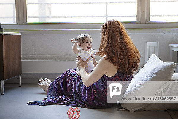 Frau spielt mit Tochter  während sie zu Hause sitzt