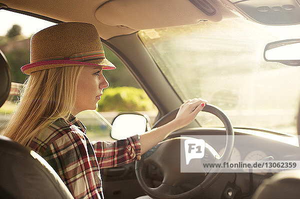 Woman in sun hat looking away while driving car