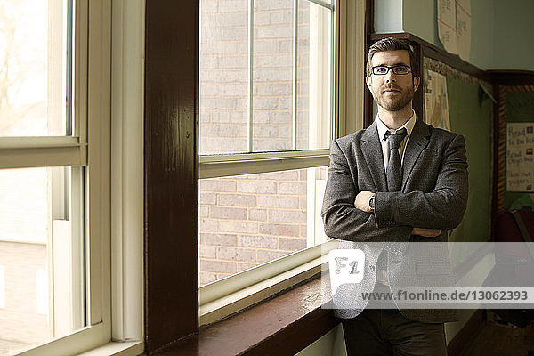 Confident businessman standing by window in office