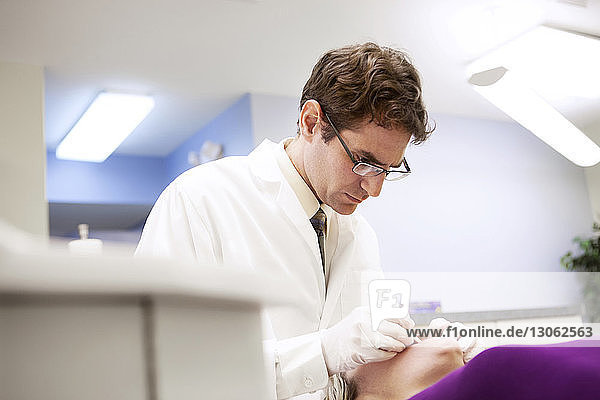 Seriöser Zahnarzt untersucht Patient in der Klinik
