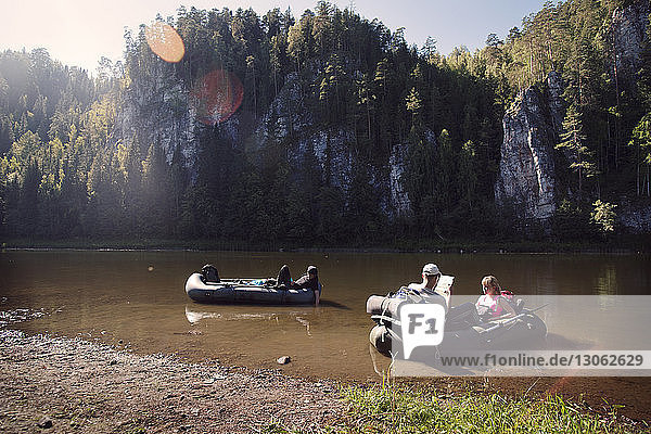 Friends sitting in raft on river against rock formations