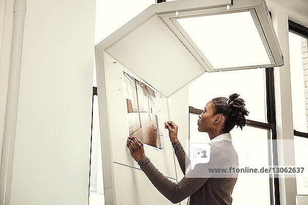 Side view of woman looking at chart while standing in office