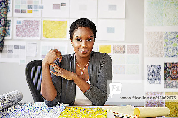 Porträt einer Modedesignerin  die in einem Workshop am Schreibtisch sitzt