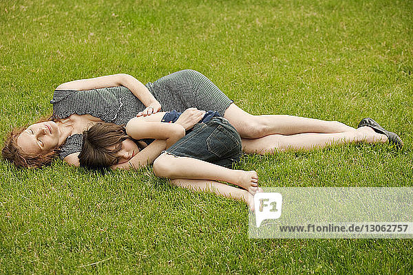 Mother and daughter sleeping at backyard