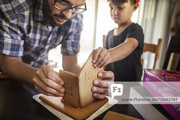 Father and son making gingerbread house at home