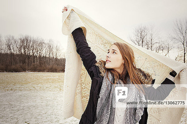 Junge Frau hält im Winter auf dem Feld eine Decke