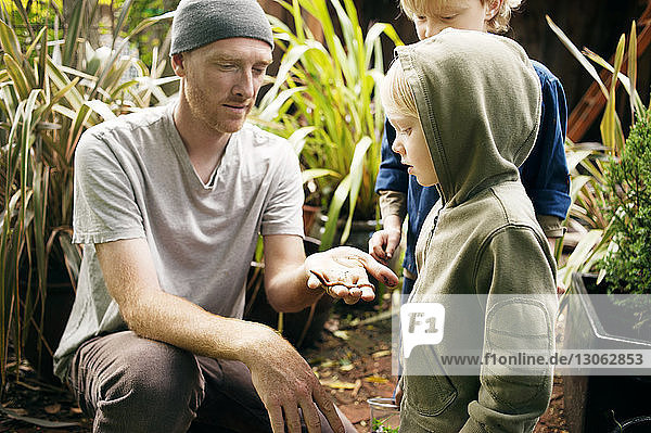 Man showing earthworm to children in garden