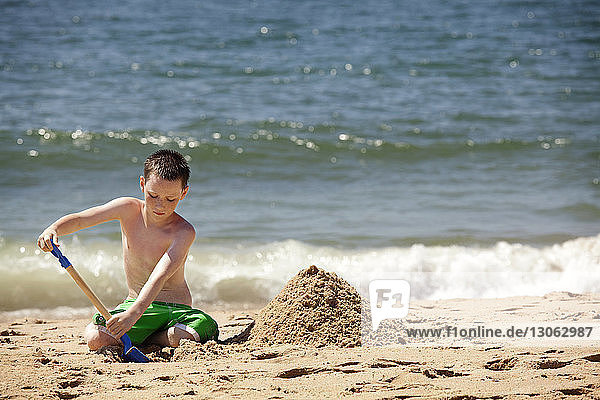 Junge spielt mit Sand am Strand