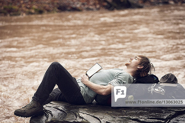 Mann schläft auf Felsen am Flussufer