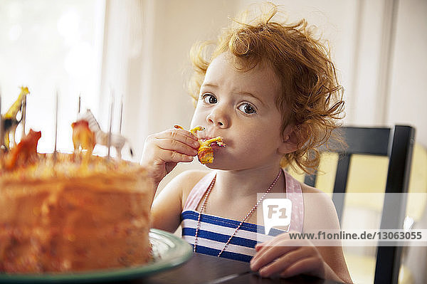 Portrait of girl eating cake while sitting at table
