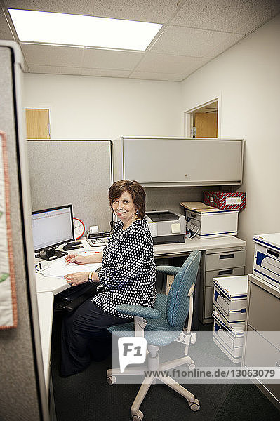 Glückliche reife Frau arbeitet am Schreibtisch im Büro