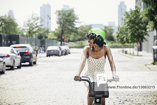 Smiling woman cycling on road in city