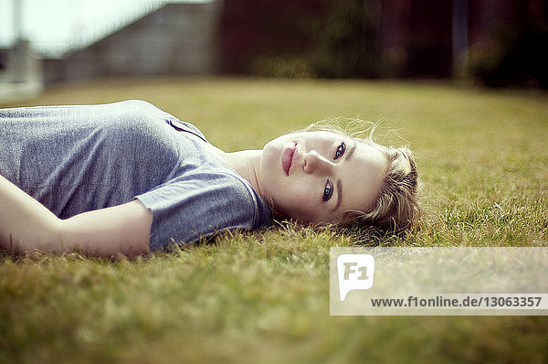 Portrait of woman lying on grassy field
