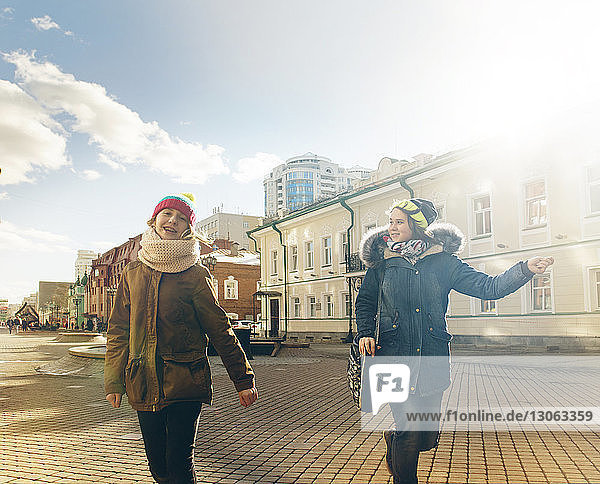 Happy friends walking on city street during sunny day