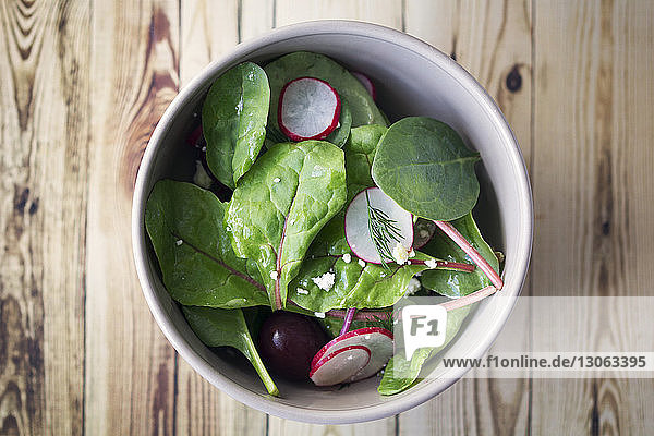 Draufsicht auf Spinat-Rettich-Salat mit Kirschen in einer Schüssel auf dem Tisch