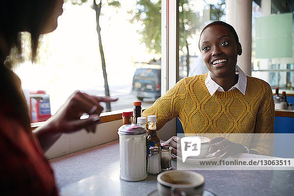 Frau hört einem Freund zu  während sie im Café sitzt