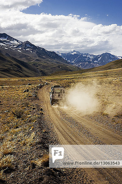 Off-road vehicle on dirt road against cloudy sky